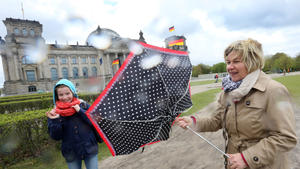 Gegen Wind und Regen versucht sich eine Berlin-Besucherin mit ihrer Tochter aus Düsseldorf am 14.04.2014 vor dem Reichstagsgebäude in Berlin zu schützen.  Foto: Stephanie Pilick/dpa +++(c) dpa - Bildfunk+++