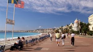 Passanten flanieren auf der Promenade des Anglais in Nizza an der französischen Riviera. Im Hintergrund rechts das Hotel Negresco. (Aufnahme von 2001).