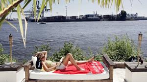 Bei strahlendem Sonnenschein genießt eine junge Frau am Dienstag (04.07.2006) in einem "Beach-Club" in Hamburg das Sommerwetter. Das warme Wetter soll auch in den kommenden Tagen anhalten. Foto: Ulrich Perrey dpa/lno +++(c) dpa - Bildfunk+++