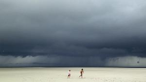 Jack Segar (R) and Finn Harden run across a deserted sandbar beach outside Barnstable Harbor as storm clouds associated with Tropical Storm Arthur pass over Cape Cod Bay behind them in Barnstable, Massachusetts, July 4, 2014. Hurricane Arthur slammed the North Carolina coast early on Friday and weakened as it moved out to sea, causing no deaths or injuries but spoiling the Independence Day holiday for thousands of Americans. REUTERS/Mike Segar (UNITED STATES - Tags: ENVIRONMENT SOCIETY)
