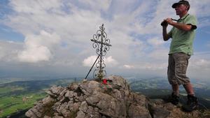 Guido Butscher steht am Donnerstag (28.08.2008) auf dem Grünten bei Rettenberg (Schwaben) mit einem Fernglas neben dem Gipfelkreuz. Auf dem auch "Wächter des Allgäus" genannten Berg herrschte enteggen der Prognosen diesiges Wetter. In den Alpen sollten Wanderer immer auch Kleidung für schlechtes Wetter mit sich führen. Foto: Stefan Puchner dpa/lby +++(c) dpa - Bildfunk+++