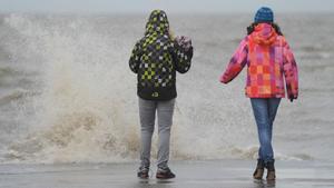 Zwei Frauen stehen am Donnerstag (05.01.2012) an der tosenden Nordsee am Fähranleger von Dagebüll. Das Tief "Andrea" beschert der Küste Sturm mit Orkanböen und eine Sturmflut. Foto: Carsten Rehder dpa/lno  +++(c) dpa - Bildfunk+++