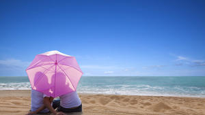 young couple romantic kissing at the beach with the umbrella, junges Paar das romantische Kuessen am Strand mit dem Regenschirm Keine Weitergabe an Drittverwerter.