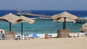 Teil einer Hotelanlage in El Quseir am Roten Meer: Der Steg im Hinterrgrund verbindet den Sandstrarnd mit Liegen, Sonnenschirmen und Windschutz und das offene Meer hinter dem Korallenriff.