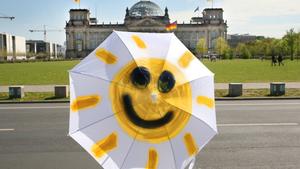 Eine lachende Sonne ist auf dem Schirm einer Passantin am Freitag (27.04.2012) vor dem Reichstagsgebäude in Berlin zu sehen. Die sommerlichen Temperaturen weit über 20 Grad sollen das ganze Wochenende über andauern. Foto: Stephanie Pilick dpa/lbn  +++(c) dpa - Bildfunk+++