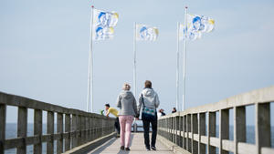 Zwei Frauen gehen am 24.04.2015 auf dem L-Beach-Festival am Weißenhäuser Strand in Wangels (Schleswig-Holstein) über die Seebrücke. In dem Ferienzentrum an der Ostsee findet das größte Frauen-Festival Europas statt. Foto: Daniel Reinhardt/dpa +++(c) dpa - Bildfunk+++