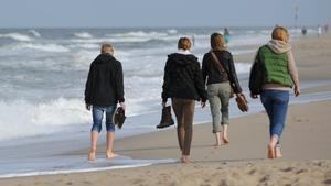 Spaziergänger gehen am Samstag (24.09.2011) auf der Nordsee-Insel Sylt barfuß am Strand von Westerland entlang. Der Herbst bringt auch in den nächsten Tagen viel Sonne und milde Temperaturen im Norden. Foto: Angelika Warmuth dpa/lno  +++(c) dpa - Bildfunk+++
