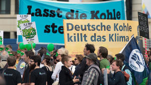 Aktivisten halten am 19.05.2015 vor dem Brandenburger Tor in Berlin am Rande des 6. Petersberger Klimadialoges Plakate mit der Aufschrift "Deutsche Kohle killt das Klima". Die Aktion der Bewegung, die sich vor allem bei Klimawandel, Menschenrechten, Tierschutz und Korruptionsbekämpfung engagiert, findet aus Anlass des Petersberger Klimadialogs statt. Foto: Soeren Stache/dpa +++(c) dpa - Bildfunk+++