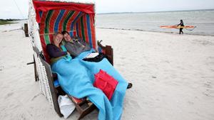 Stephan und Andrea aus Greifswald sitzen am Donnerstag (21.07.2011) bei windigem Wetter mit Decken in einem Strandkorb in Stein (bei Laboe) an der Ostsee. Nach Angaben der Meteorologen soll die Sonne in den kommenden Tagen bei Temperaturen um 19 Grad Celsius nur selten zu sehen sein. Foto: Bodo Marks dpa/lno  +++(c) dpa - Bildfunk+++