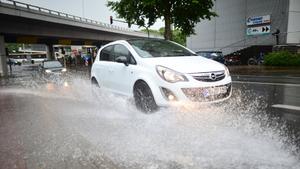 Ein Auto fährt am 27.06.2015 während einem Gewitter mit Starkregen durch in Mainz (Rheinland-Pfalz) durch eine Pfütze. Foto: Julian Stratenschulte/dpa +++(c) dpa - Bildfunk+++