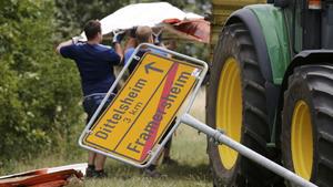 Men clear away debris next to the broken sign to the village of Framersheim near Mainz, Germany, July 8, 2015, following tornado. A tornado that was triggered by violent storms following a period of unusually warm weather touched down in the village last night.    REUTERS/Wolfgang Rattay   
