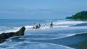Eine Gruppe Menschen rennen aus dem Meer an einem natürlichen Strand mit Wellen.