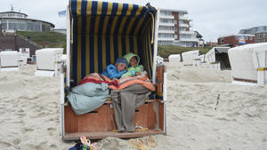 Zwei junge Mädchen aus Bayern liegen am 01.09.2015 auf der Insel Wangerooge (Niedersachsen) bei stürmischen Wind warm eingepackt im Strandkorb. Foto: Carmen Jaspersen/dpa +++(c) dpa - Bildfunk+++