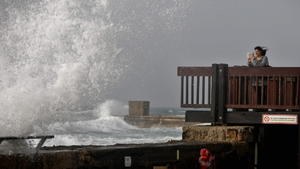 epa04613254 An Israeli woman takes images with a mobile device while watching the waves of the Mediterranean Sea breaking at a wave breaker in the port of Tel Aviv, on a windy day in Israel, 10 February 2015. EPA/ABIR SULTAN +++(c) dpa - Bildfunk+++