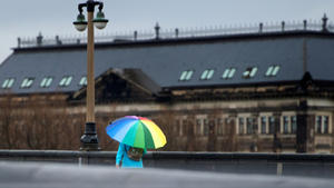 Eine Frau mit einem bunten Regenschirm geht am 17.11.2015 bei Regenwetter über die Augustusbrücke in Dresden (Sachsen). Foto: Arno Burgi/dpa +++(c) dpa - Bildfunk+++