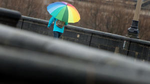 ARCHIV - Ein Frau mit einem bunten Regenschirm geht am 17.11.2015 bei Regenwetter über die Augustusbrücke in Dresden (Sachsen). Am 1. Dezember beginnt der meteorologische Winter - doch frostiges Wetter ist nicht in Sicht. Foto: Arno Burgi/dpa (zu lsn «Kalter Winter lässt auf sich warten» vom 28.11.2015) +++(c) dpa - Bildfunk+++