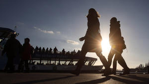 Passanten gehen am 06.12.2015 bei Sonnenschein an den Landungsbrücken in Hamburg an einer Hafenfähre entlang. Foto: Bodo Marks/dpa +++(c) dpa - Bildfunk+++