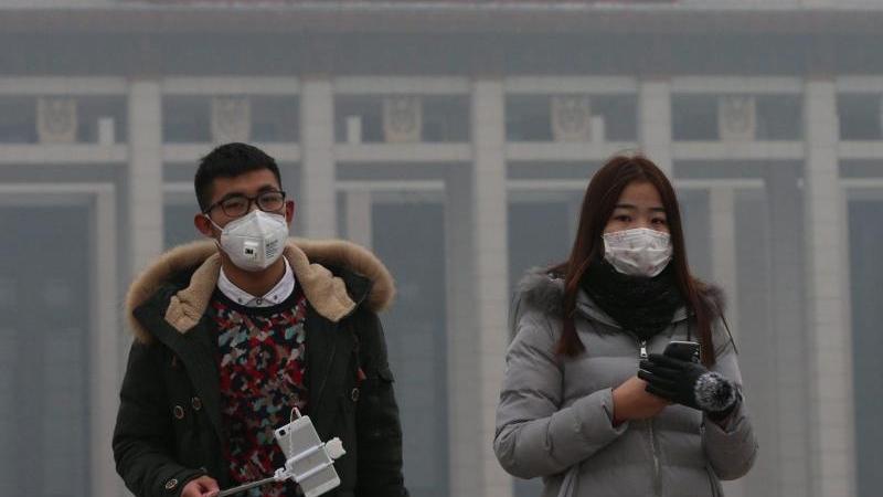 Touristen in Peking tragen Masken, um ihre Lungen vor den alarmierenden Feinstaubwerten zu schützen. Medien und Bevölkerung sind kritischer gegenüber der immensen Luftverschmutzung. Es ist das erste Mal, dass in Peking die Smog-Alarmstufe "Rot" ausge