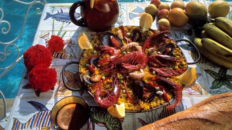 Wie im Urlaub: Eine Pfanne des spanischen Reisgerichts Paella reichlich belegt mit Meeresfrüchten, dazu leckeres Weißbrot und Sangria mit frischen Früchten. Aufnahme von 1992.