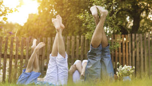 Happy young family showing legs outside in green nature.