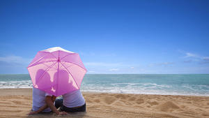 young couple romantic kissing at the beach with the umbrella, junges Paar das romantische Kuessen am Strand mit dem Regenschirm Keine Weitergabe an Drittverwerter.