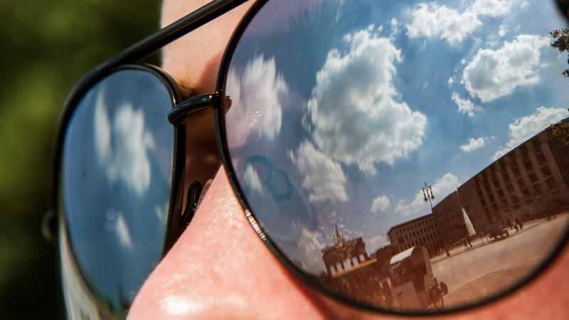 In der Sonnenbrille der Australierin Alice spiegeln sich am 24.06.2016 in Berlin das Brandenburger Tor, blauer Himmel und einige Wolken. Foto: Paul Zinken/dpa +++(c) dpa - Bildfunk+++