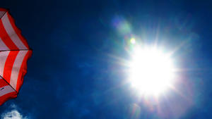 ARCHIV - Ein rot-weiß gestreifter Sonnenschirm steht am 06.08.2015 geöffnet auf einem Balkon in Dresden (Sachsen), während die Sonne vom blauen Himmel scheint. Foto: Arno Burgi/dpa (zu dpa "Umfrage: Für die Mehrheit waren die Sommer früher besser" vom 07.07.2016) +++(c) dpa - Bildfunk+++
