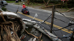 A motorcyclists ride past a fallen utility pole and trees damaged by Typhoon Nepartak, in Taitung, Taiwan July 9, 2016. REUTERS/Tyrone Siu