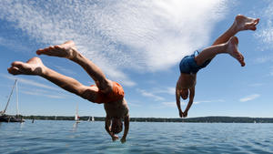 Zwei junge Männer springen am 10.07.2016 in Starnberg (Bayern) am Starnberger See ins Wasser. Foto: Tobias Hase/dpa +++(c) dpa - Bildfunk+++