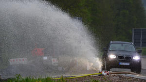 Ein Fahrzeug fährt am 06.05.2013 in Elzach (Baden-Württemberg) an einem Schlauch vorbei, aus dem abgepumptes Wasser spritzt. Ein schweres Unwetter hat in Elzach für Überschwemmungen und Schäden gesorgt. Foto: Patrick Seeger/dpa +++(c) dpa - Bildfunk+++
