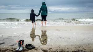 Eine Mutter steht mit ihrer Tochter im Regen am Strand von Gedesby (Dänemark), aufgenommen am 19.07.2015. Foto: Thomas Eisenhuth/dpa | Verwendung weltweit