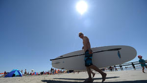 ARCHIV - Ein Stand-Up-Paddler trägt am 21.07.2013 sein Surfboard zurück an den Strand in St. Peter-Ording (Schleswig-Holstein). Nach einem sehr wechselhaften Sommer sorgt Hoch «Gerd» auch im Norden Deutschlands in den kommenden Tagen für einen versöhnlichen Ausklang der Saison. Foto: Marcus Brandt/dpa (zu dpa «Sonne pur im Norden: Der Sommer kehrt zurück» vom 24.08. +++(c) dpa - Bildfunk+++