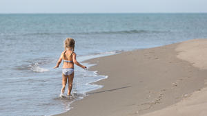 Girl runs along the beach at the water's edge