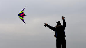 Eine junge Frau nutzt am 14.10.2016 am Nordseedeich von Büsum (Schleswig-Holstein) den starken Wind, um ihren Lenkdrachen steigen zu lassen. Foto: Carsten Rehder/dpa +++(c) dpa - Bildfunk+++
