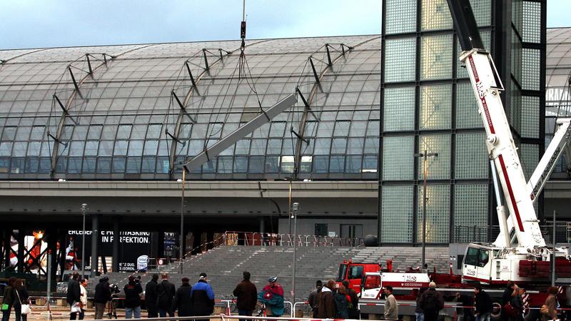 ARCHIV - Zahlreiche Schaulustige sehen zu, wie am 19.01.2007 der Stahlträger (Bildmitte), der in der Nacht zuvor durch den Orkan "Kyrill" vom Hauptbahnhof in Berlin gestürzt war und sich in der Fassade verkeilt hatte, mit Hilfe eines Krans geborgen u
