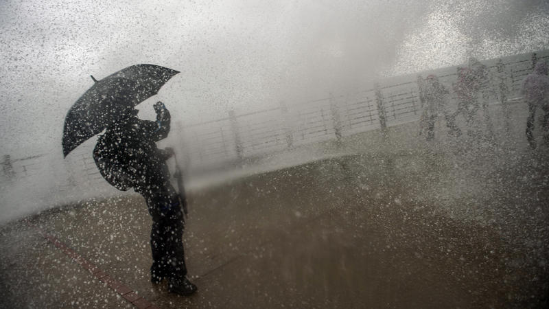 Ein Mann steht am 05.02.2017 bei starkem Regen, mit einem Schirm, an der «New Promenade» in San Sebastian (Spanien), um eine hohe Welle, die über die Promenade schwappt, zu fotografieren. Nordspanien hat seit einigen Tagen Sturmböen von bis zu 120 km