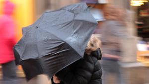 Schmuddelwetter mit Regen und Sturmboeen in Muenchen Passanten haben grosse Muehe mit ihren Regenschirm en, Bayern, Deutschland | Verwendung weltweit
