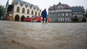 Ein Helfer geht am 26.07.2017 in Goslar (Niedersachsen) über den überfluteten Marktplatz in der historischen Altstadt.   Dauerregen hat im südlichen Niedersachsen in einigen Orten zu Überschwemmungen geführt. Foto: Swen Pförtner/dpa +++(c) dpa - Bildfunk+++