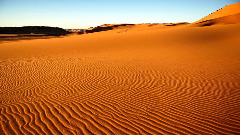 Ein Sandfeld auf dem Hochplateau des Gilf Kebir im Abendlicht.