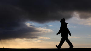 Unter dunklen Sturmwolken geht ein kleines Mädchen am 08.02.2016 auf der Molenmauer im Ostseebad Warnemünde (Mecklenburg-Vorpommern) entlang. Foto: Bernd Wüstneck/dpa | Verwendung weltweit