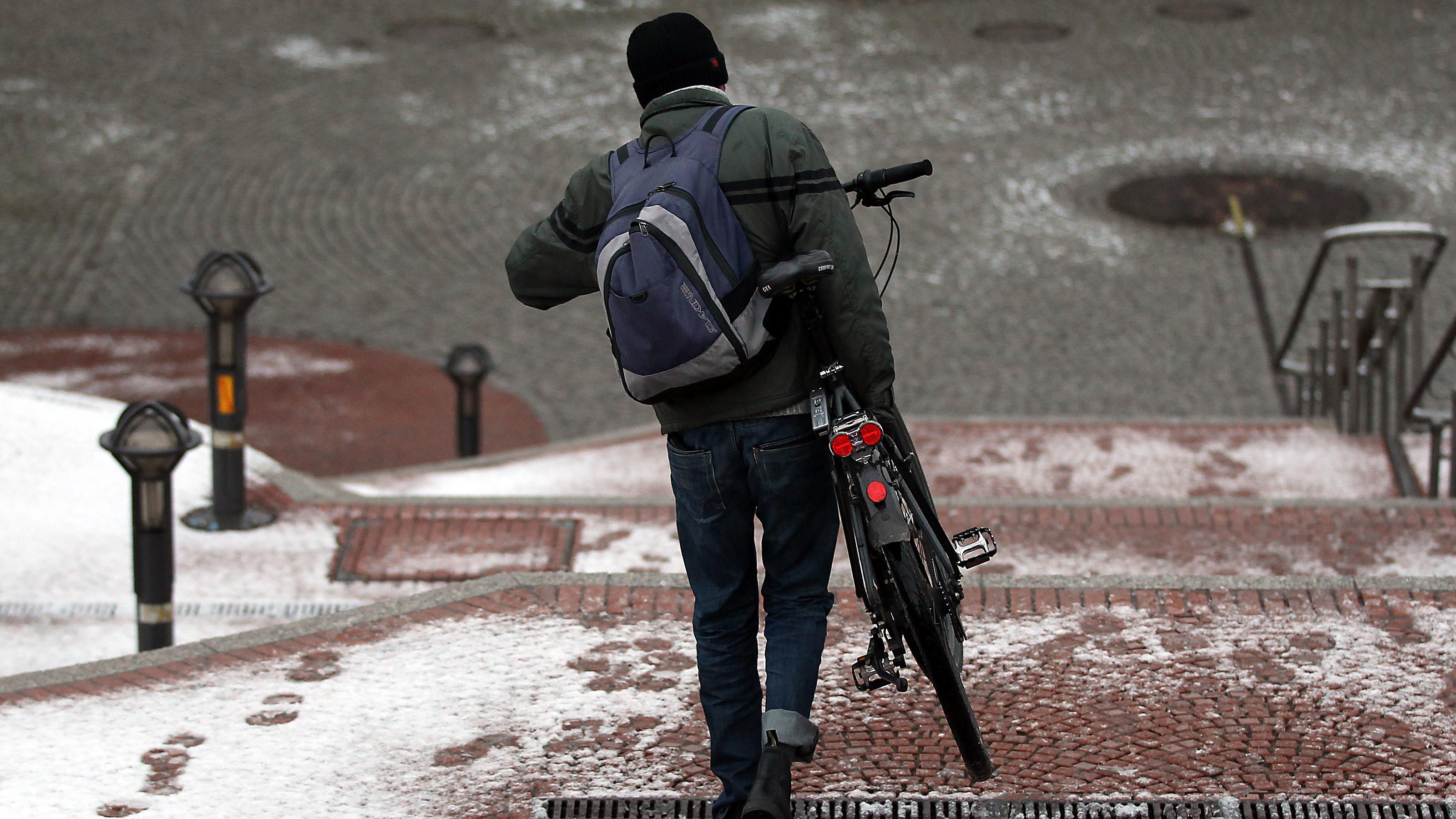 Ein Mann trägt am Freitagmorgen (26.11.2010) in Köln sein Fahrrad durch den Schnee. Leichte Niederschläge am frühen Morgen haben in Köln für den ersten Schnee im Flachland gesorgt. Foto: Oliver Berg dpa/lnw | Verwendung weltweit