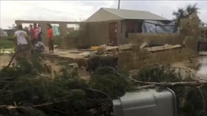 13.02.2018, Tonga, Nuku·alofa: Das Video-Standbild zeigt Menschen neben einem vom Wirbelsturm «Gita» demolierten Haus. Windstößen von mehr als 200 Kilometern pro Stunde zieht Sturm «Gita» über den Inselstaat Tonga im Südpazifik. (Bestmögliche Qualität) Foto: Uncredited/TVNZ/dpa +++ dpa-Bildfunk +++