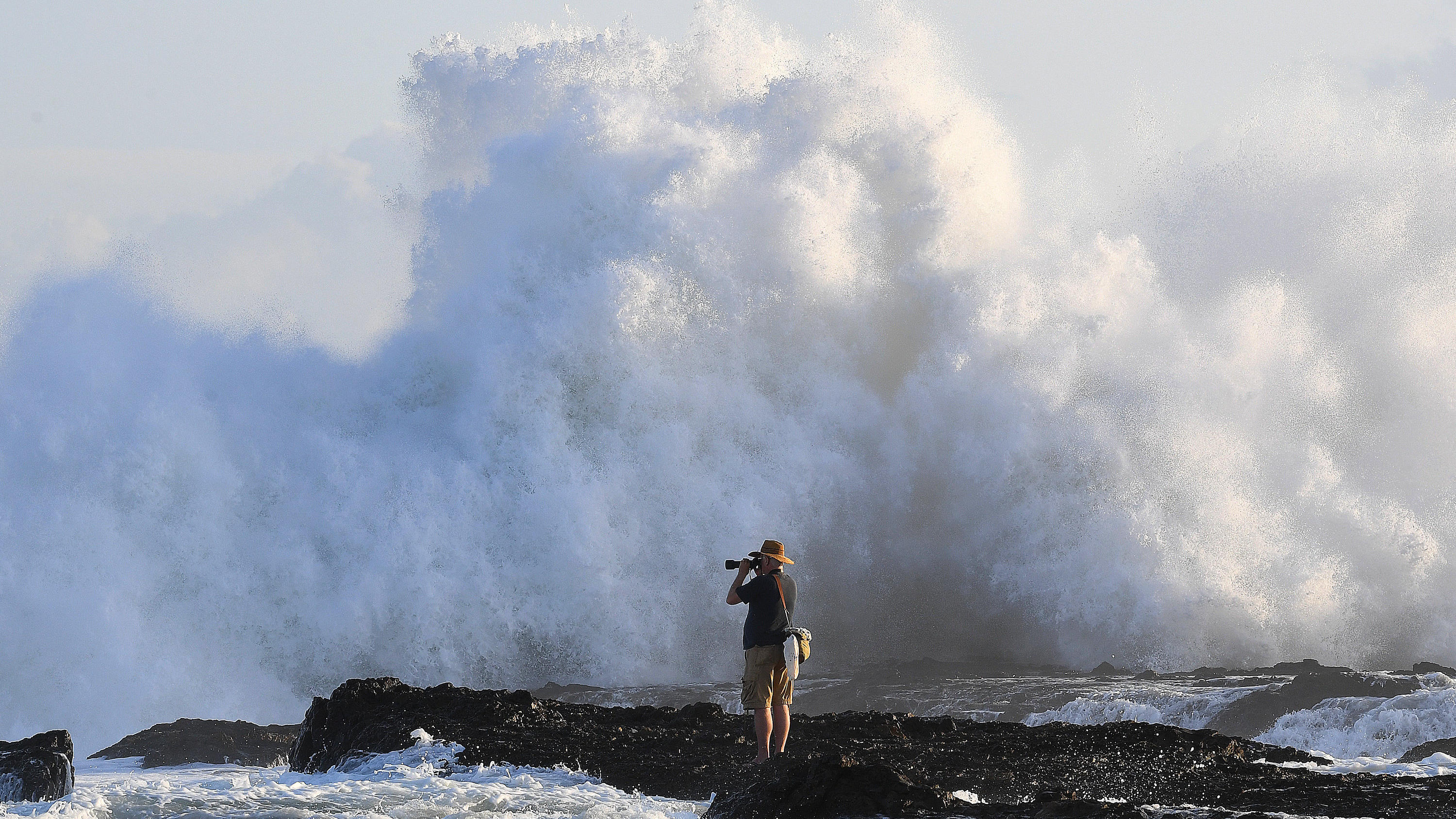 dpatopbilder - 17.02.2018, Australien, Queensland, Gold Coast: Ein Fotograf wartet nahe den Snapper Rocks vor der Brandung auf den richtigen Augenblick. Die großen Wellen des Pazifik an der Ostküste sind auch ein Ergebnis des Tropen-Sturms Gita, der vor wenigen Tagen auf den Inseln von Tonga Zerstörungen anrichtete. Foto: Dave Hunt/AAP/dpa +++ dpa-Bildfunk +++